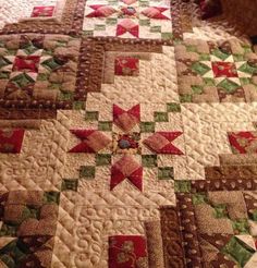 a close up of a quilt on a bed with red, green and white stars