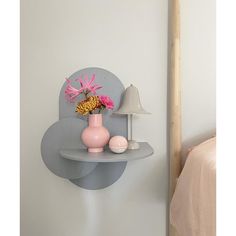 a vase with flowers on a shelf next to a lamp and bed in a room