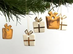 three ornaments hanging from a christmas tree with gold and white bows on them, each ornament has a gift tag attached to it