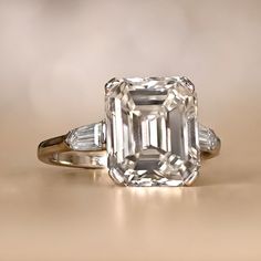 an emerald cut diamond ring with baguettes on the sides and tapered shoulders