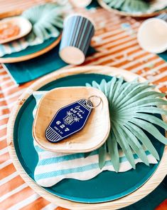 a blue and white place setting with palm leaves on the plate, plates and napkins