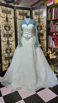 a wedding dress is displayed in front of a bookcase