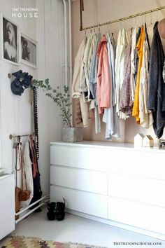 a white dresser sitting next to a wall filled with clothes