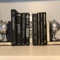 a row of books sitting on top of a white shelf next to a silver globe