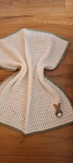 a crocheted blanket laying on top of a wooden floor next to a teddy bear