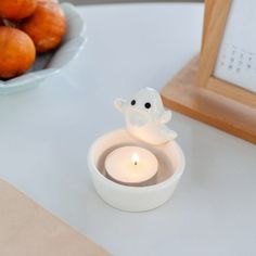 a small white candle sitting on top of a table next to a bowl of donuts