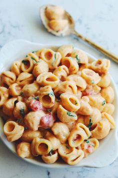 a white bowl filled with macaroni and cheese on top of a marble counter