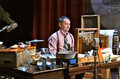 a man sitting at a desk in front of an old fashioned sewing machine and other items