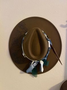 Be stylishly western with the Western Sun hat. This unique piece features a brown, wide brim hat with a bandana and hand burned design, giving you classic western vibes. Stay fashionably in-the-know with the Western Sun. Brown Felt Hat For Rodeo, One Size, Brown Felt Hat For Rodeo, One Size Fits Most, Southwestern Brown Felt Hat With Curved Brim, Brown Southwestern Fedora Hat, Southwestern Brown Fedora Hat, Southwestern Style Brown Fedora Hat, Brown Southwestern Felt Hat With Curved Brim, Country Style Brown Hat Bands For Festivals, Brown Flat Brim Felt Hat For Festivals