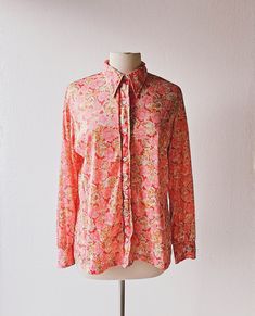 "A vintage 1970s Vera Neumann blouse with a dense print of pink flowers and gold and silver dandelions against a red background. *label: Vera *label is faded and blurred, but I think it reads 100% nylon; the fabric is a lightweight, semi-sheer, silky-feeling jersey *button up front; collar stays; long sleeves with buttons and gathers at banded cuffs; straight bottom hem *excellent condition--no holes, stains or tears! Size is too faded to read; blouse measures like a US women's L. Measurements: Vintage Floral Print Shirt For Fall, Red Floral Print Retro Shirt, Red Vintage Print Top For Spring, Red Retro Floral Print Shirt, Retro Red Floral Print Shirt, Red Vintage Print Shirt, Red Top With Vintage Print For Spring, Red Vintage Shirt With Vintage Print, Retro Pink Printed Shirt