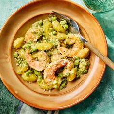 a bowl filled with shrimp and broccoli on top of a blue table cloth