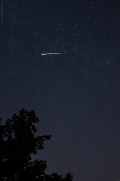 the night sky is filled with stars and an object in the distance, as well as trees