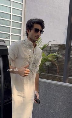 a man in sunglasses is standing next to a car