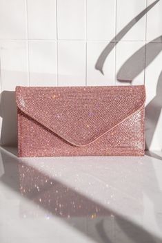 Not to be dramatic, but everyone needs this clutch! The Quentin Pink Rhinestone Envelope Purse features a pink rhinestone and vegan leather fabric, a light pink satin lining, a pink vegan leather back, a silver detachable shoulder chain, a snap button closure, and an inside card holder. Lined.;  Purse measures 9" wide, 5" tall, and 1" deep;  Man made materials.; Prom Bag, Prom Purse, Glitter Purse, Glitter Clutch, Envelope Purse, Rhinestone Clutch, Pink Clutch, Wedding Purse, Pink Prom