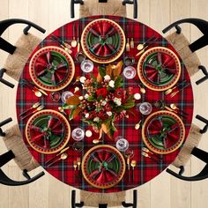 an overhead view of a christmas table setting with red and green plaid napkins, silver place settings, and black metal utensils