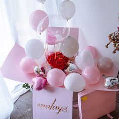 balloons and confetti are on display in a pink box