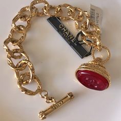 Chanel Vintage Autumn 1993 (93a) Gripoix Charm Bracelet. The Red Pate De Verre Poured Glass Gripoix Wax Seal Fob Has The Signature Cc At The Center. Atop The Fob Is The Chanel Oval Cartouche Stating “Chanel 93a Made In France”. This Piece Reigns From The Era Of Karl Lagerfeld And Victoire De Castellane. It Features Large Gold Plated Chased Open Links, Chanel Signed Toggle Clasp And The Beautiful Ornate Setting For The Gripoix Wax Seal. Even More Remarkable, Are The Original Store Tags Attached F