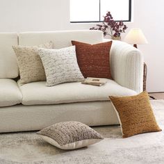 a living room with a white couch and several pillows on the floor in front of it