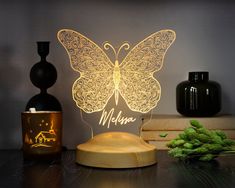 a lamp with a butterfly on it sitting next to some vases and other items