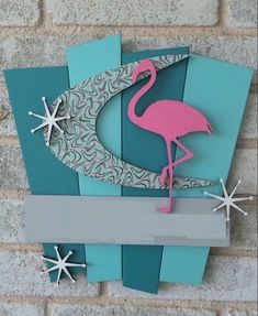 a pink flamingo standing on top of a blue and gray block with snowflakes