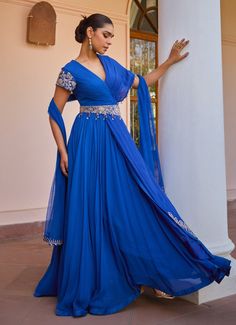 Introducing the timeless Blue Layered Anarkali Gown with Dupatta, crafted from georgette organza. The captivating blue gown features a vibrant hue that exudes elegance and sophistication. Adorned with intricate tilla work, dori, pearls, handmade tassels, brass sequins, and beads, it offers a touch of luxurious detail. The detachable embroidered belt accentuates the waist, creating a flattering silhouette. The soft net dupatta complements the gown, adding an ethereal layer to the outfit. With a s Anarkali Gown With Dupatta, Anarkali Georgette, Isha Gupta, Wedding Guest Attire, Gown With Dupatta, Embroidered Belt, Vacuum Storage, Indian Wedding Wear, Anarkali Gown