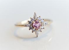 Skylar - Pink Sapphire solid 14k gold with 0.2 ct Diamond, White Sapphire or CZ, Pink Sapphire Halo Cluster Ring, Sapphire Engagement Ring by EmiConnerJewelry on Etsy https://www.etsy.com/listing/607513019/skylar-pink-sapphire-solid-14k-gold-with Heirloom Pink Sapphire Wedding Ring, Heirloom Style Pink Sapphire Wedding Ring, Pink Cluster Ring With Halo Setting, Pink Round Cut Cluster Ring Fine Jewelry, Pink Sapphire Ring With Halo, Pink Cluster Ring With Round Cut For Gift, Pink Cluster Ring With Brilliant Cut, Heirloom Pink Sapphire Ring For Wedding, Wedding Pink Sapphire Ring In Yellow Gold