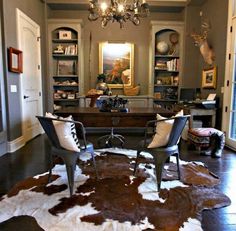 a living room filled with furniture and a cow hide rug