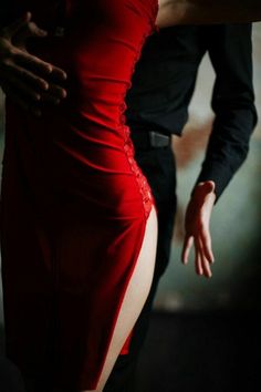 a woman in a red dress standing next to a man