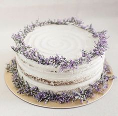 a cake with white frosting and lavender sprinkles on top is sitting on a gold plate