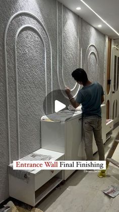 a man standing on top of a white counter next to a wall mounted dryer