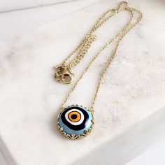 Introducing our stunning Cable Chain with a Hand-Painted 19mm Evil Eye Turkish Pendant in a Decorative Prong Setting. This gold Evil Eye Necklace is the perfect addition to any jewelry collection, with its unique design and intricate detailing. Crafted with care, this necklace features an 18+2 inch chain and a hand-painted Turkish pendant measuring 19mm in size. The evil eye symbol is said to ward off negative energy and bring good luck, making this necklace both beautiful and meaningful. Our Ca Yellow Gold Enamel Medallion Necklace, Gold Plated Round Amulet Charm Necklace, Gold-tone Amulet Round Pendant Jewelry, Handmade Yellow Gold Enamel Necklaces, Gold-tone Round Pendant Amulet Jewelry, Handmade Yellow Gold Enamel Necklace, Blue Round Pendant Chain Jewelry, Blue Round Pendant Jewelry With Chain, Spiritual Round Gold-plated Necklaces