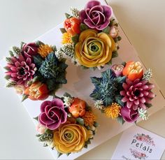 three cupcakes decorated with flowers on top of a card