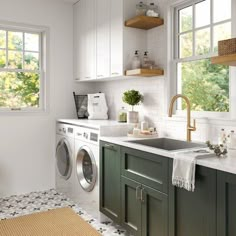 a washer and dryer in a small room with white walls, blue cabinets and flooring