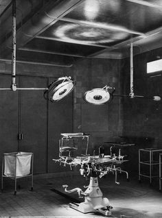 an old black and white photo of medical equipment in a room with lights on the ceiling