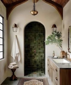 a bathroom with a green tile shower and white counter tops, along with a rug on the floor