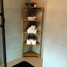 a corner shelf with three rolls of toilet paper on it in the corner of a bathroom