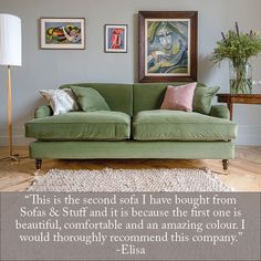 a green couch sitting on top of a wooden floor next to a lamp and pictures