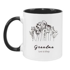 a black and white coffee mug with the words grandma on it, in front of an image of flowers