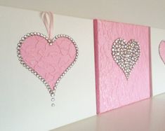 three pink hearts are hanging on the wall next to each other, and one is decorated with pearls