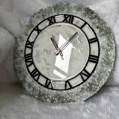 a marble clock with roman numerals on it's face sitting on white fur