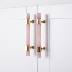 two pink glass door handles on white cabinets