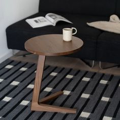 a coffee table with a cup on it in front of a black couch and checkered rug