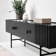 a black and white sideboard with two vases sitting on it's sides