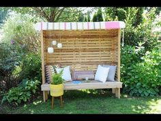 a wooden bench sitting in the middle of a lush green field next to bushes and trees