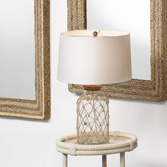 a table with a lamp on it next to a mirror and two framed pictures hanging on the wall