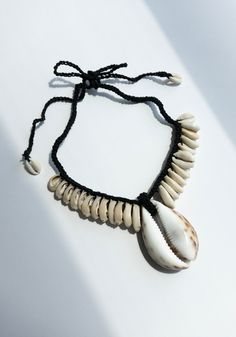 a black string bracelet with white seashells on it