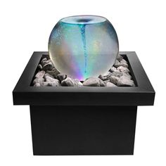 a fish bowl sitting on top of a black box filled with rocks and gravel in it