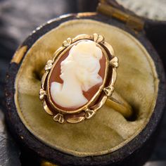 This sweet ring holds an oval shell cameo in a bezel setting, with a decorated goldwork frame. The ring is crafted in 10k yellow gold and currently fits a size 2.75. This ring will likely have limitations for how many sizes it can increase, so please feel free to call with sizing inquiries. Elegant Luxury Oval Cabochon Dome Ring, Luxury Heirloom Jewelry With Fluted Bezel, Luxury Vintage Oval Cabochon Dome Ring, Bezel Set Cabochon, Sweet Ring, Cameo Ring, Gold Work, Yellow Gold Rings, Bezel Setting