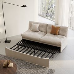 a white couch sitting on top of a wooden floor next to a table and lamp