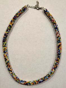 "This gorgeous beaded crochet necklace would make a perfect accessory for any outfit. This necklace was made with Aunt Lydia's crochet thread fine 20 which is made from 100% mercerized cotton. I used size 11 seed beads to crochet this necklace. It has one bead cap on either end and a lobster clasp on one side and an extender chain on the other. The necklace is about 16\" long (40.64cm) not including the extender. With the extender it measures about 18\" (45.72cm). It is also about a 1/4\" (0.635cm) thick." Multicolor Crochet Necklaces, Adjustable Crochet Necklaces With Round Beads, Beaded Crochet Necklace, Crochet Dinosaur, Beaded Crochet, Crochet Thread, Rainbow Crochet, Bobble Stitch, Crochet Rose